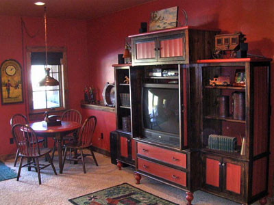 Inredning av ett rustikt mellanstort allrum med öppen planlösning, med ett bibliotek, orange väggar, mörkt trägolv och en dold TV