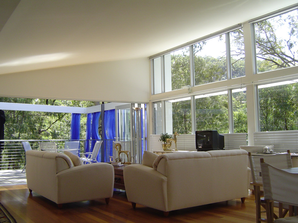 Diseño de salón para visitas cerrado y abovedado costero pequeño con paredes blancas, suelo de madera clara y televisor independiente