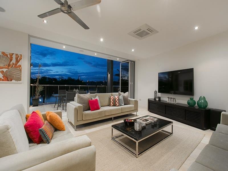 Large modern open plan living room in Brisbane with white walls, travertine flooring, no fireplace, a wall mounted tv and multi-coloured floors.