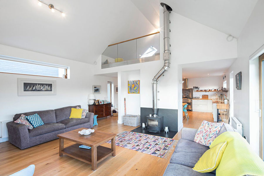 This is an example of a large scandinavian mezzanine living room in Dublin with white walls, light hardwood flooring, a wood burning stove and a tiled fireplace surround.