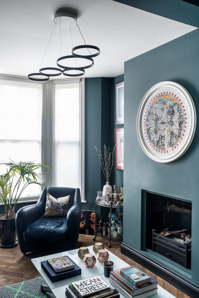 ロンドンにあるお手頃価格の小さなエクレクティックスタイルのおしゃれな独立型リビング (青い壁、無垢フローリング、標準型暖炉、レンガの暖炉まわり、テレビなし、茶色い床) の写真