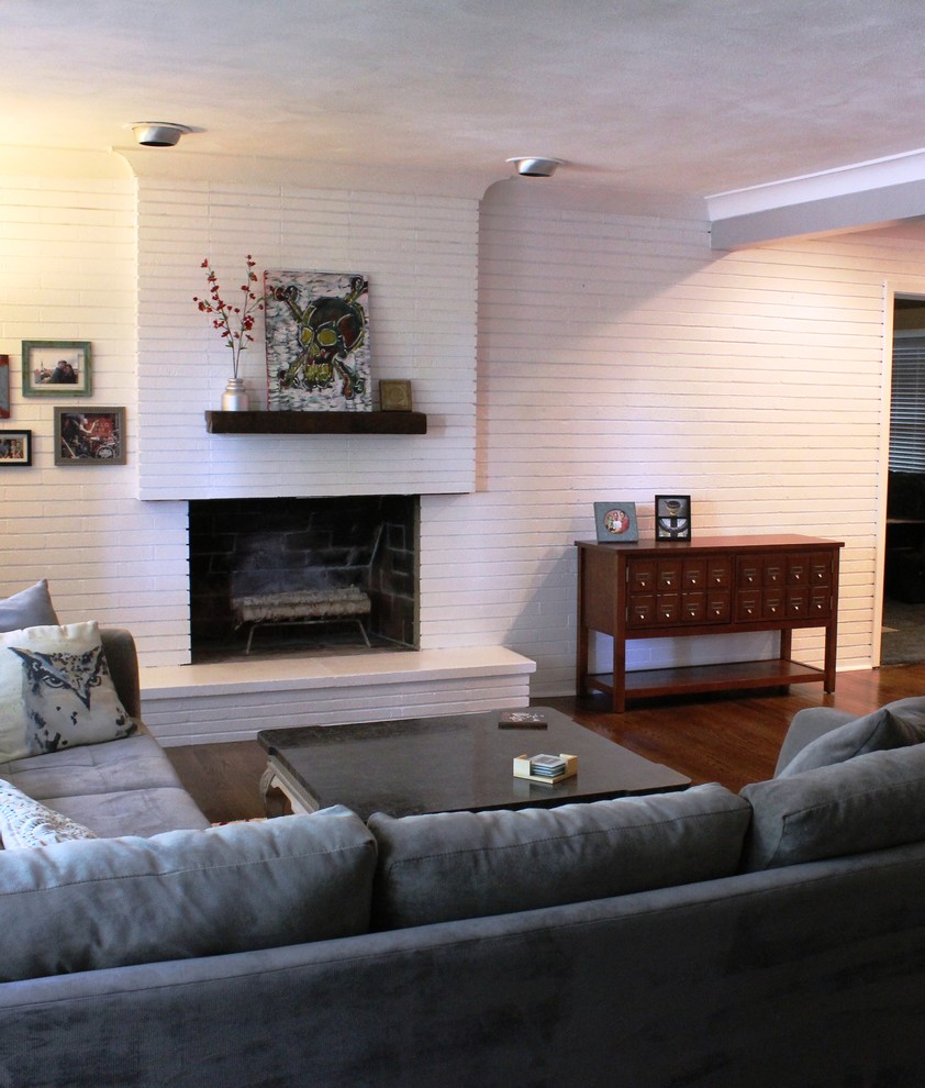 На фото: открытая гостиная комната среднего размера в стиле неоклассика (современная классика) с белыми стенами, паркетным полом среднего тона, стандартным камином и фасадом камина из кирпича с