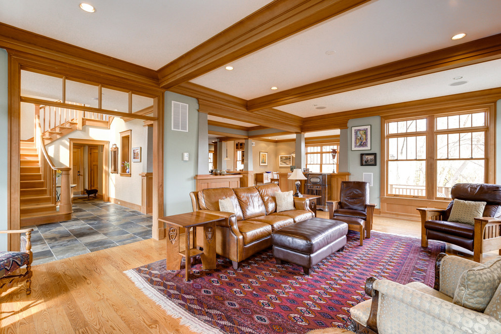 Diseño de salón abierto de estilo americano grande con paredes grises, suelo de madera en tonos medios y suelo marrón