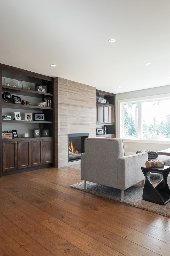 Photo of a large contemporary open plan living room in Vancouver with grey walls, medium hardwood flooring, a standard fireplace, a stone fireplace surround and a concealed tv.