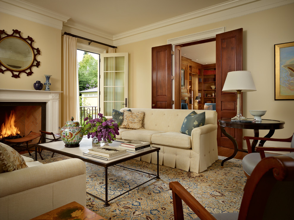 На фото: гостиная комната в классическом стиле с бежевыми стенами, паркетным полом среднего тона и стандартным камином