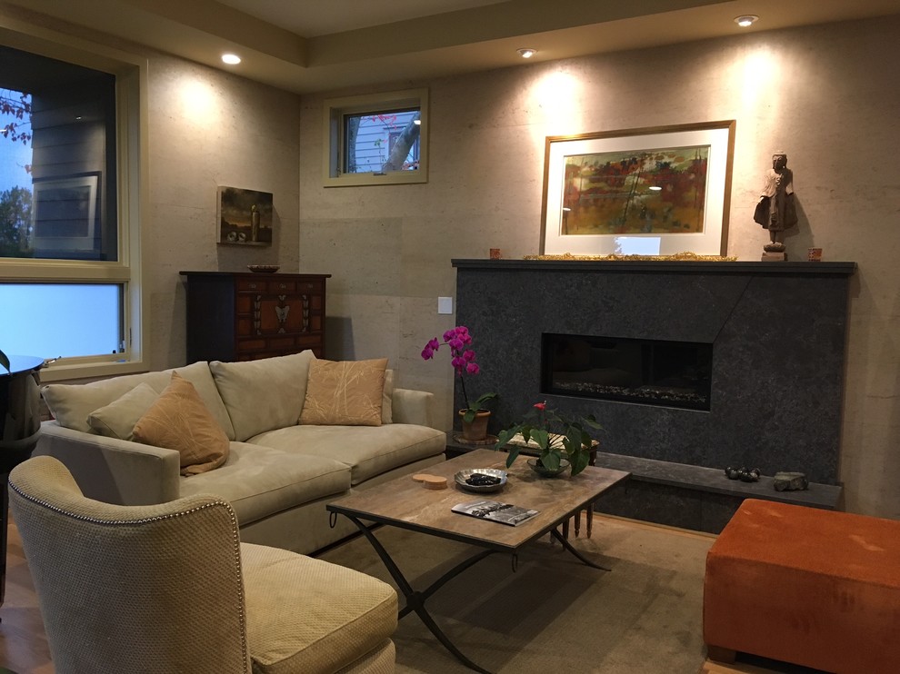 Mittelgroßes, Abgetrenntes Modernes Wohnzimmer mit beiger Wandfarbe, Kalkstein, Kamin, Kaminumrandung aus Beton und braunem Boden in Seattle