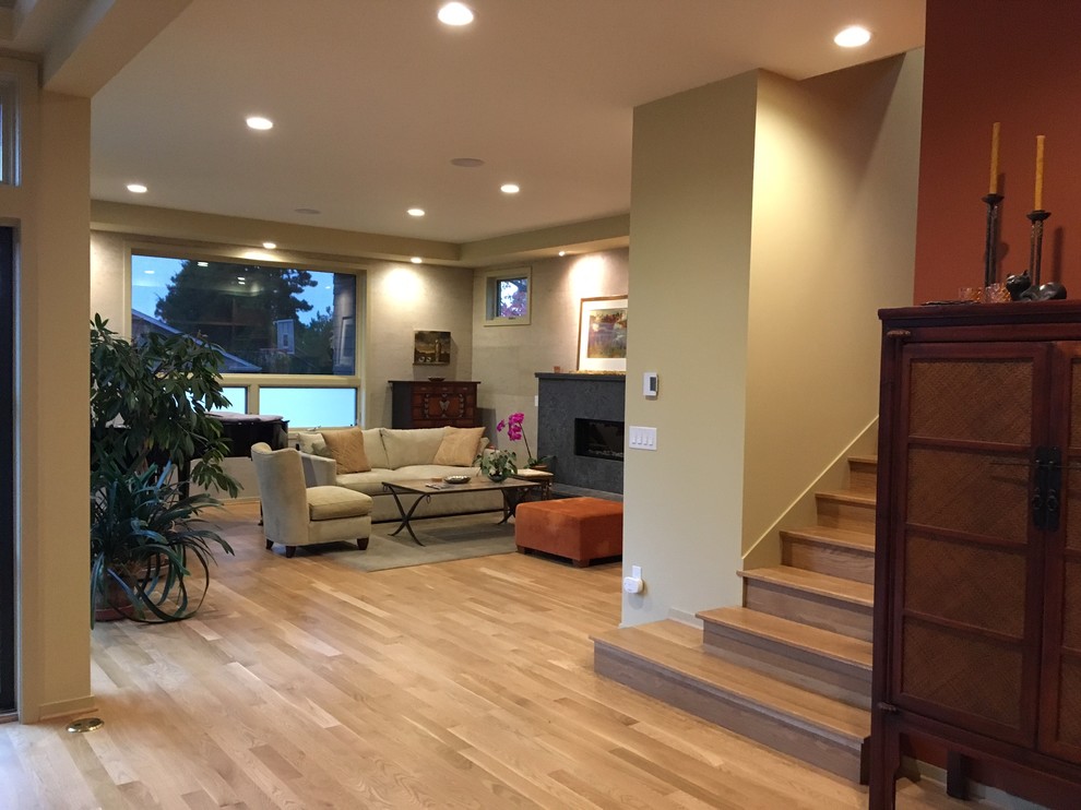 Example of a mid-sized trendy enclosed limestone floor and brown floor living room design in Seattle with beige walls, a standard fireplace and a concrete fireplace