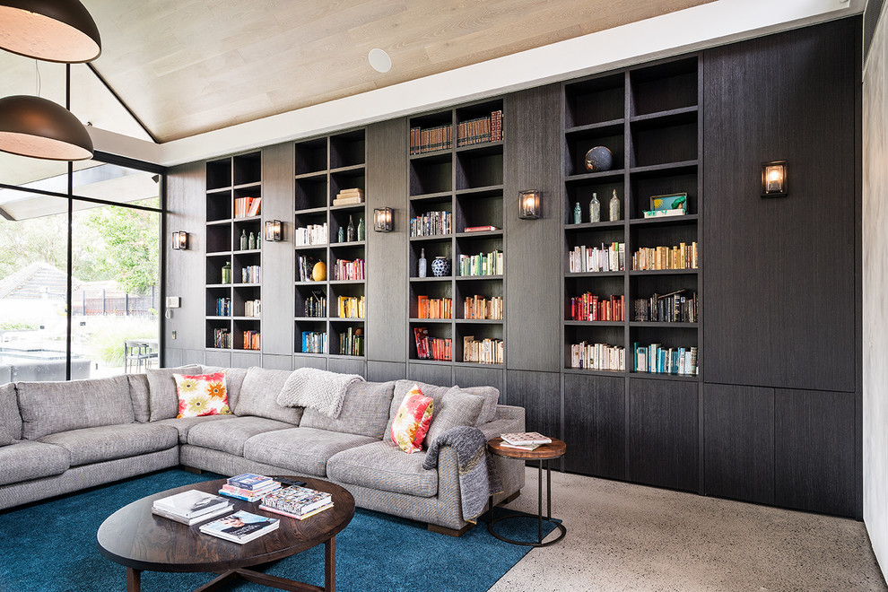 Esempio di un grande soggiorno design chiuso con libreria, pareti bianche, pavimento in cemento, nessun camino e pavimento grigio