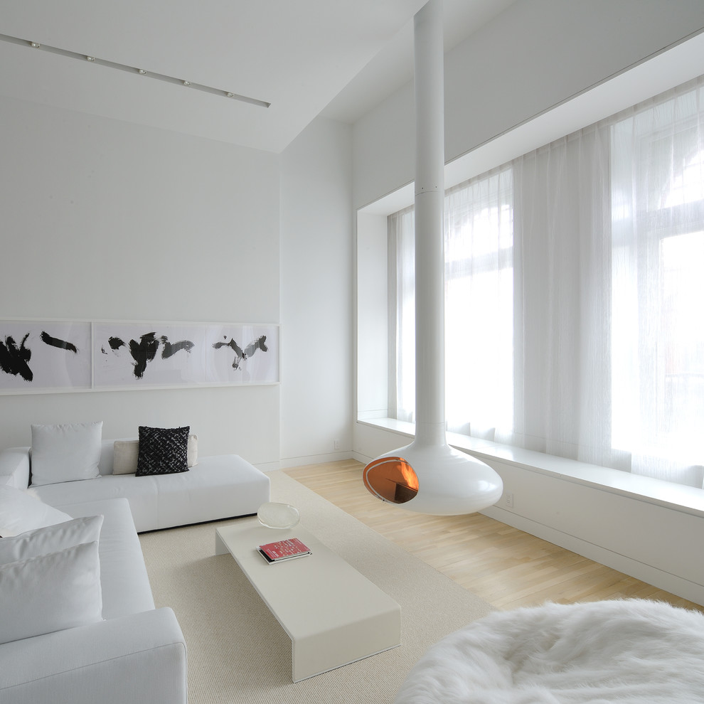 На фото: гостиная комната в скандинавском стиле с белыми стенами, светлым паркетным полом и подвесным камином с