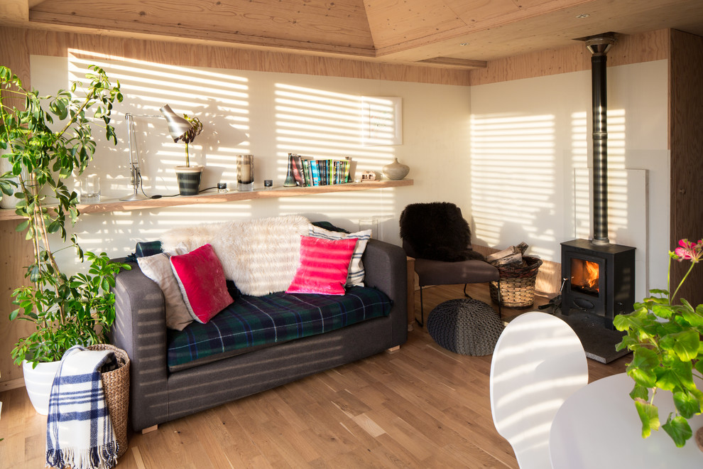 Imagen de salón abierto rústico pequeño con paredes blancas, suelo de madera en tonos medios y estufa de leña