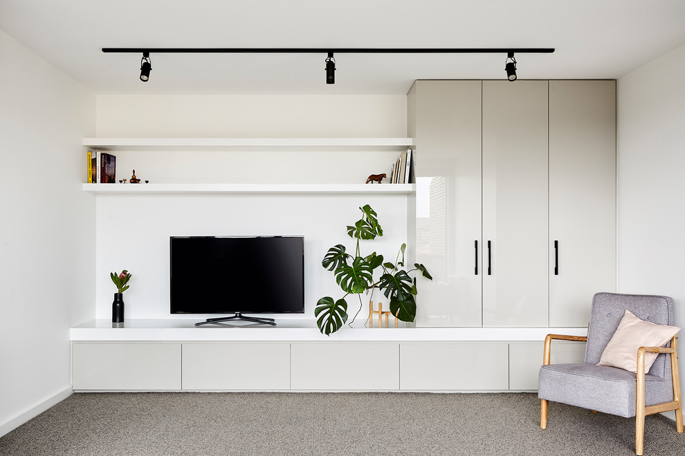 Diseño de biblioteca en casa abierta actual pequeña con paredes blancas, moqueta, televisor independiente y suelo gris