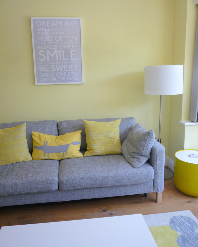 Bild på ett mellanstort funkis separat vardagsrum, med gula väggar, mellanmörkt trägolv, en spiselkrans i trä, en väggmonterad TV och en standard öppen spis
