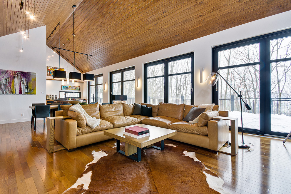 Cette photo montre un salon tendance ouvert avec un sol en bois brun et un plafond cathédrale.
