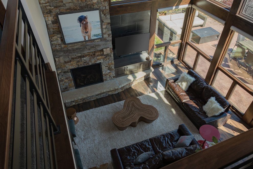 Mittelgroßes Stilmix Wohnzimmer mit dunklem Holzboden, Kamin, Kaminumrandung aus Stein, TV-Wand und braunem Boden in Denver