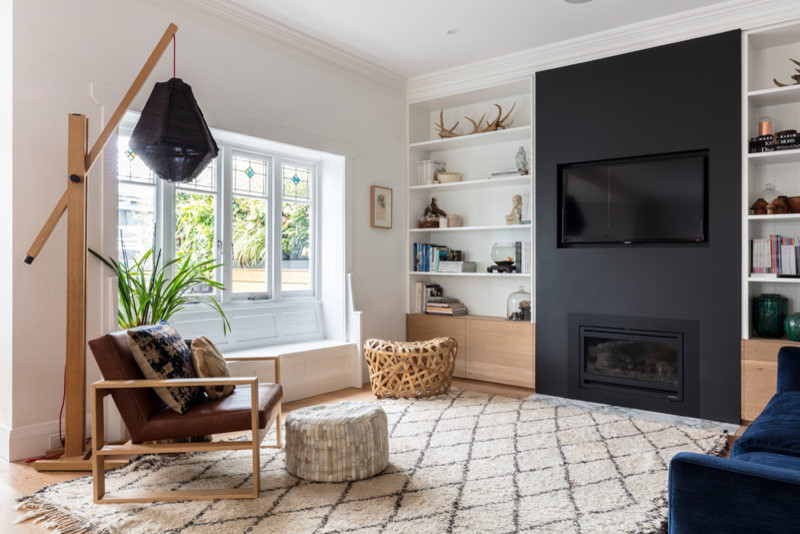 Großes, Offenes Maritimes Wohnzimmer mit schwarzer Wandfarbe, braunem Holzboden, Kamin, verputzter Kaminumrandung, TV-Wand und braunem Boden in Sydney