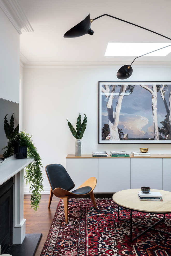 Свежая идея для дизайна: изолированная гостиная комната среднего размера в стиле неоклассика (современная классика) с белыми стенами, паркетным полом среднего тона, стандартным камином, фасадом камина из штукатурки и телевизором на стене - отличное фото интерьера