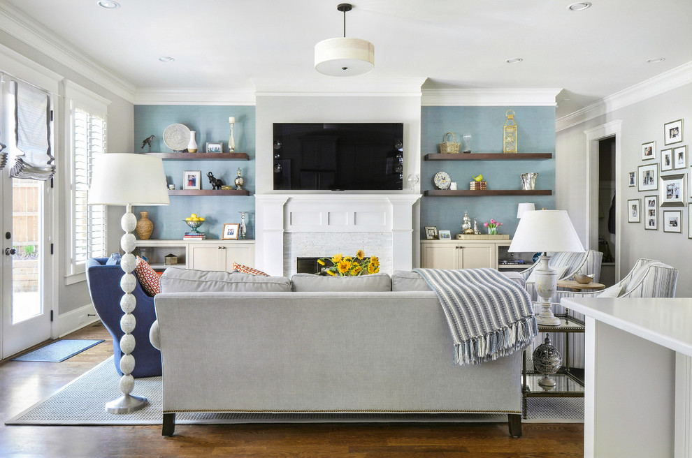 На фото: открытая гостиная комната среднего размера в стиле неоклассика (современная классика) с синими стенами, паркетным полом среднего тона, стандартным камином, фасадом камина из камня, телевизором на стене и коричневым полом