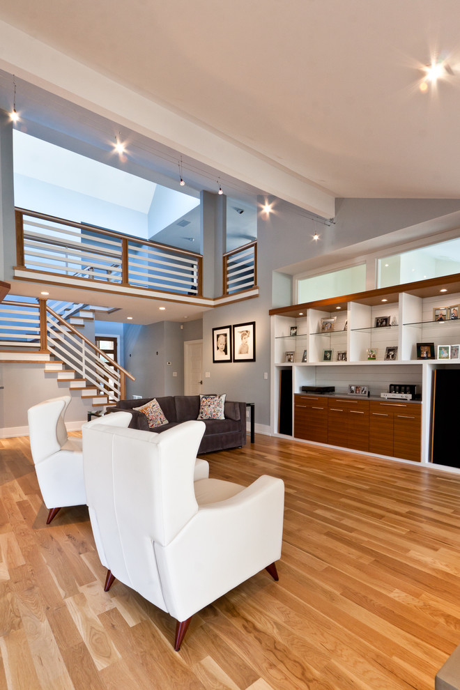 Cette photo montre un grand salon tendance ouvert avec un mur gris, un sol en bois brun, une cheminée double-face, un manteau de cheminée en carrelage et un téléviseur encastré.