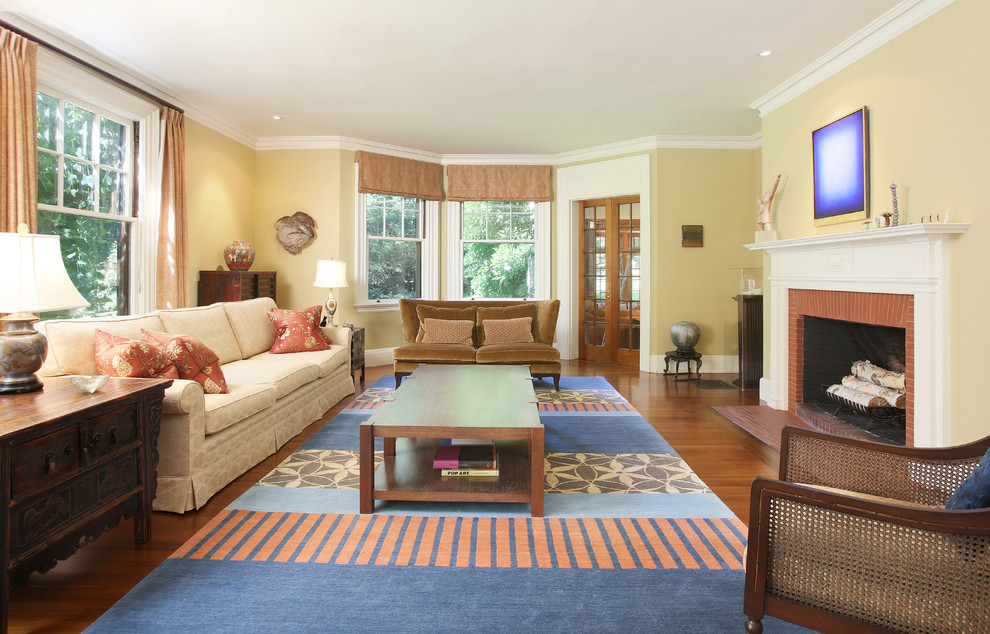 На фото: большая изолированная гостиная комната в классическом стиле с желтыми стенами, паркетным полом среднего тона, стандартным камином и фасадом камина из дерева с