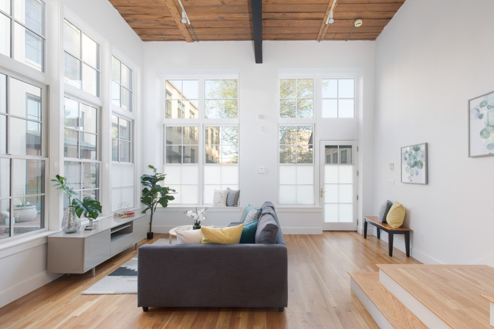 Großes, Fernseherloses, Offenes Skandinavisches Wohnzimmer mit weißer Wandfarbe, braunem Holzboden und beigem Boden in Boston