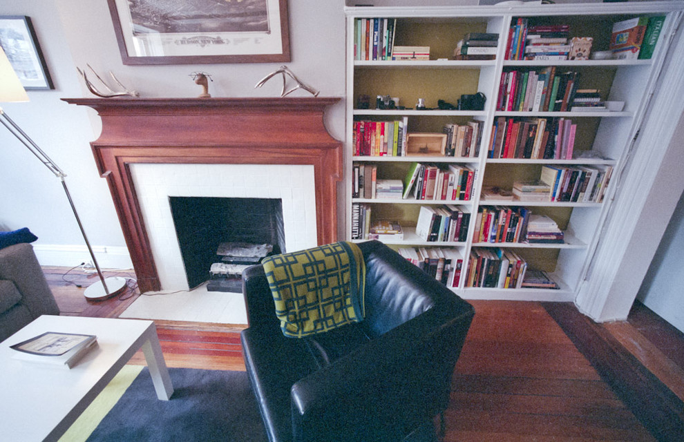 Foto di un soggiorno minimal chiuso con libreria, pareti beige, parquet scuro e camino classico