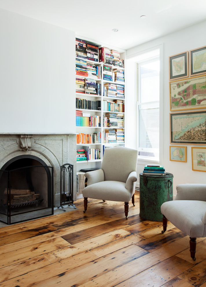 Exemple d'un salon tendance de taille moyenne et ouvert avec une bibliothèque ou un coin lecture, un mur blanc, un sol en bois brun, une cheminée standard et un manteau de cheminée en pierre.