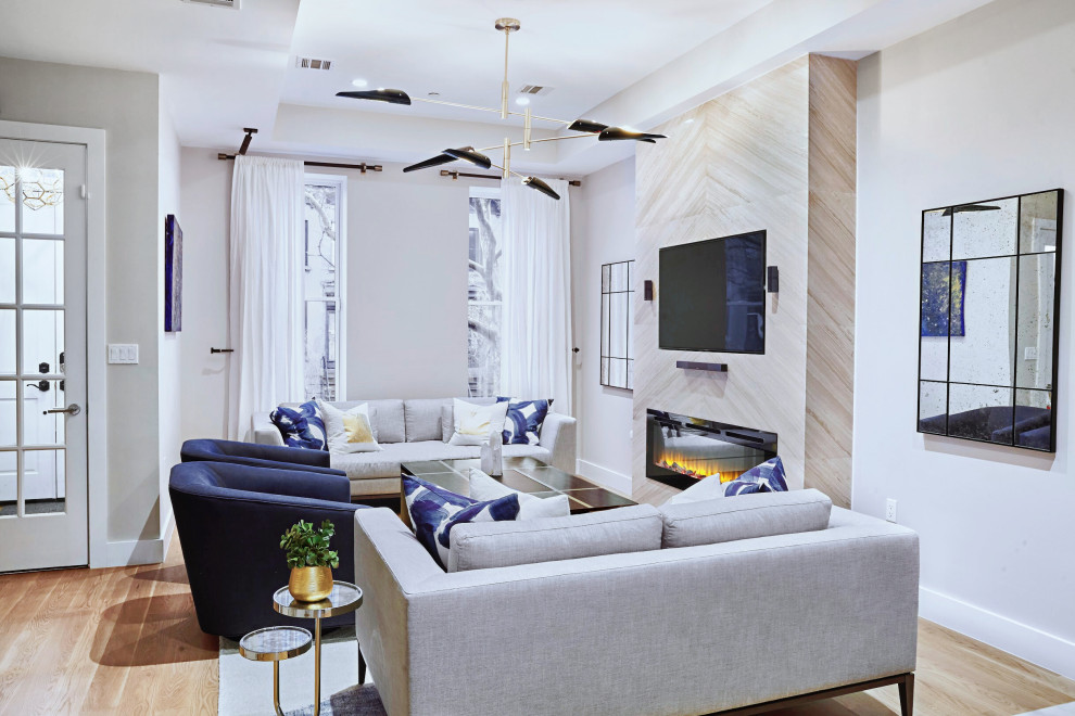 Aménagement d'un grand salon moderne ouvert avec un mur beige, parquet clair, cheminée suspendue, un manteau de cheminée en pierre et un téléviseur encastré.