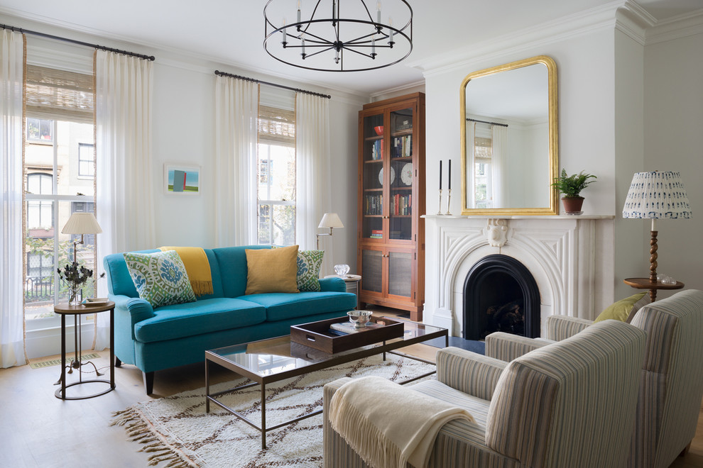 Пример оригинального дизайна: парадная гостиная комната в стиле неоклассика (современная классика) с белыми стенами, стандартным камином и синим диваном без телевизора
