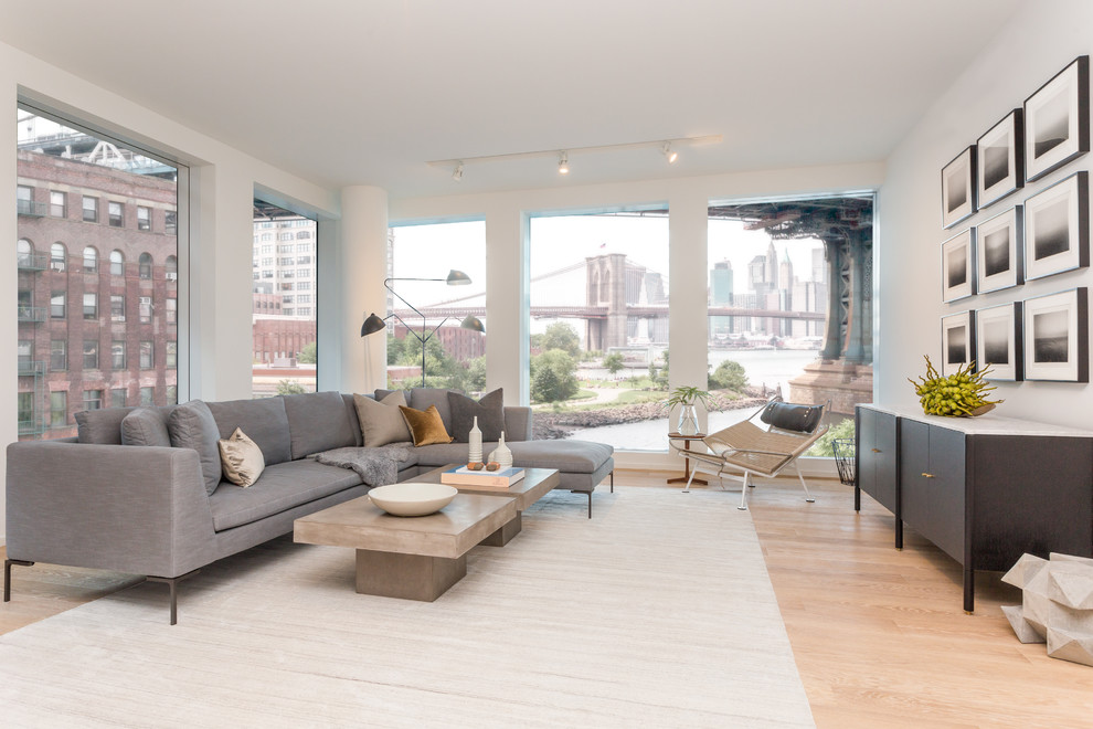 Large contemporary formal mezzanine living room in New York with white walls, light hardwood flooring, no fireplace and no tv.