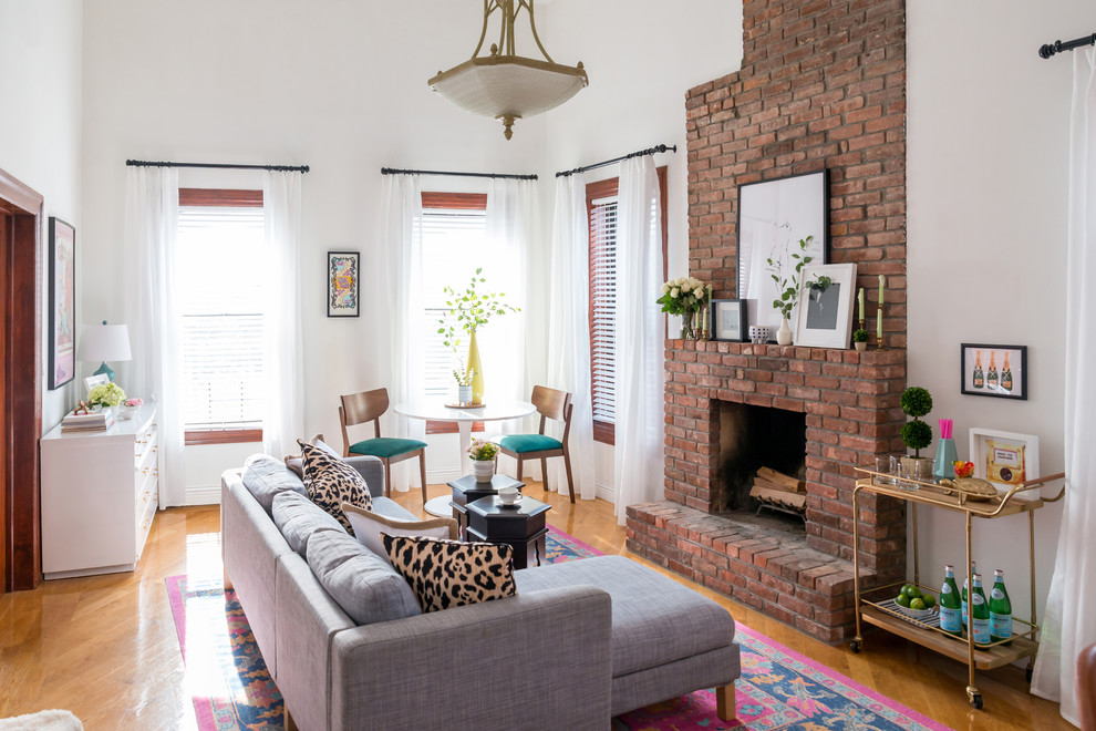 Fernseherloses Stilmix Wohnzimmer mit weißer Wandfarbe, braunem Holzboden, Kamin und Kaminumrandung aus Backstein in New York