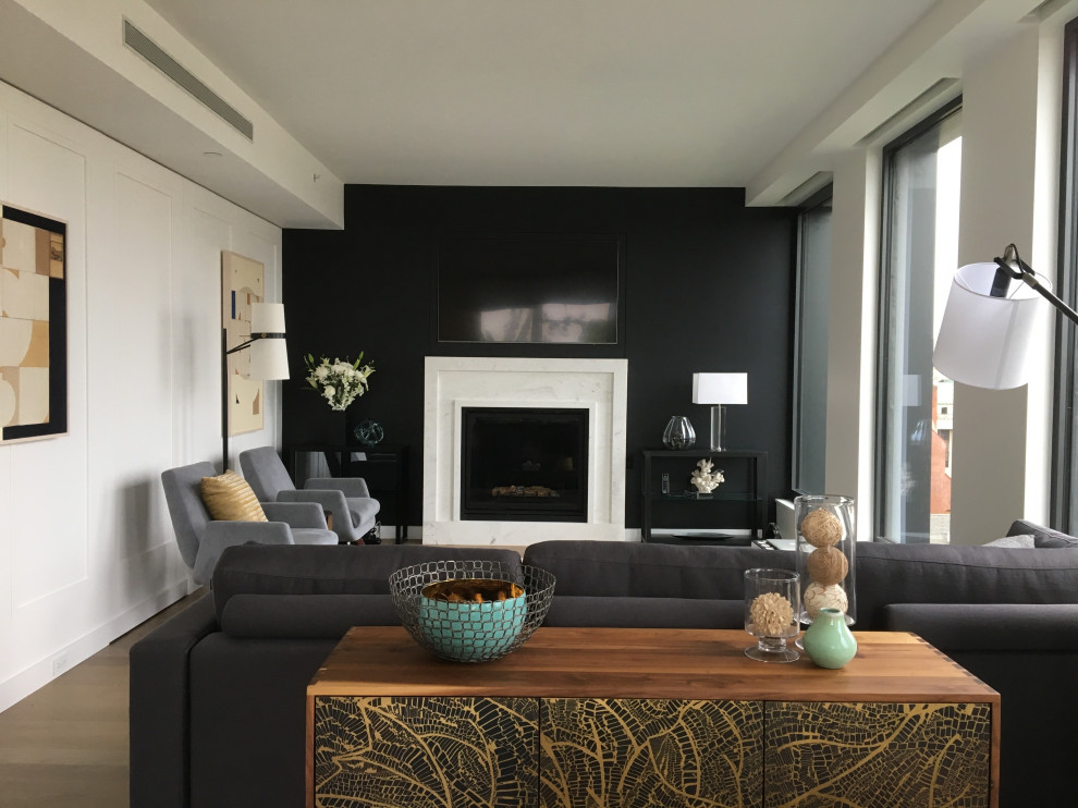 Пример оригинального дизайна: большая открытая гостиная комната в стиле ретро с черными стенами, светлым паркетным полом, стандартным камином, фасадом камина из камня, скрытым телевизором, коричневым полом и панелями на части стены