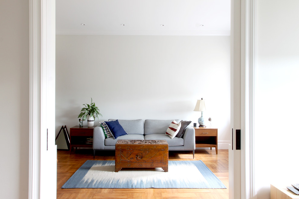 На фото: гостиная комната в стиле неоклассика (современная классика) с серыми стенами и паркетным полом среднего тона