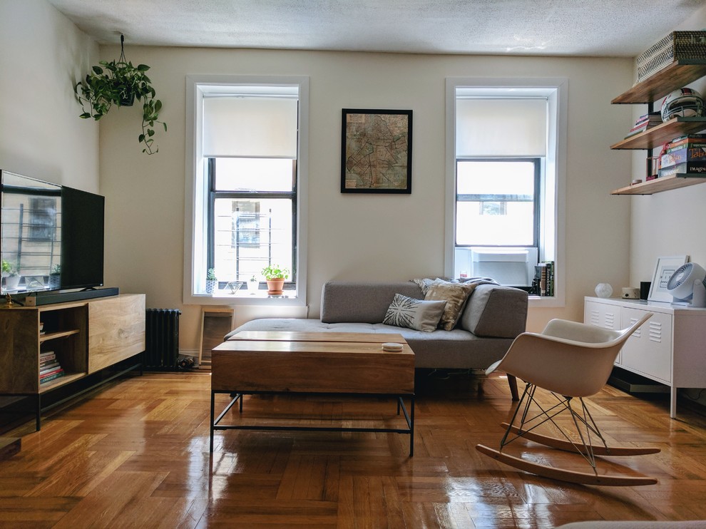 Kleines, Offenes Nordisches Wohnzimmer mit weißer Wandfarbe, braunem Holzboden und freistehendem TV in New York