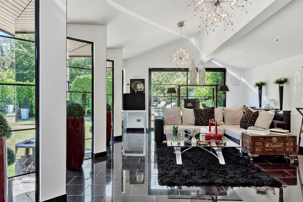 This is an example of a bohemian formal open plan living room in Hertfordshire with white walls and black floors.