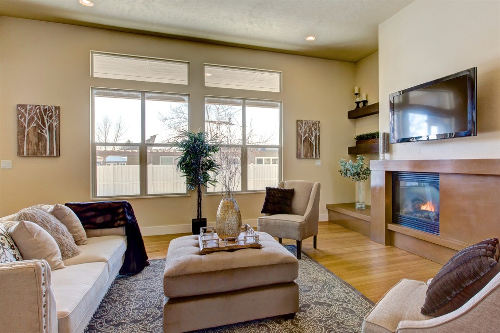 This is an example of a medium sized traditional formal open plan living room in Boise with beige walls, bamboo flooring, a standard fireplace, a concrete fireplace surround and a wall mounted tv.