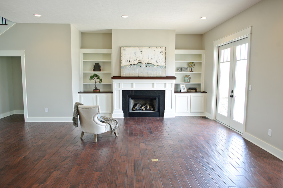 Example of a mid-sized classic formal and open concept dark wood floor living room design in Indianapolis with beige walls, a standard fireplace, a wood fireplace surround and no tv
