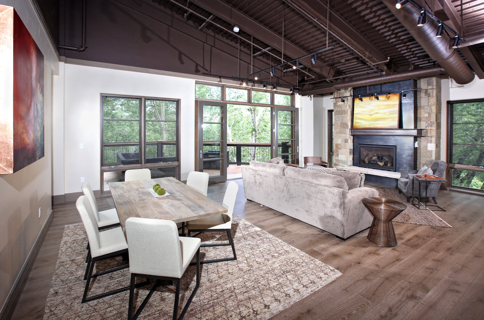 Cette photo montre un salon industriel ouvert avec un sol en bois brun, un mur blanc et une cheminée ribbon.