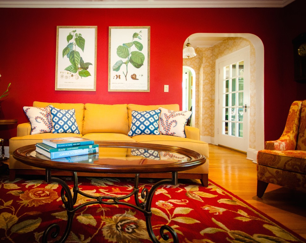 Immagine di un soggiorno classico di medie dimensioni con pareti rosse, pavimento in legno massello medio, camino classico, cornice del camino in legno e nessuna TV
