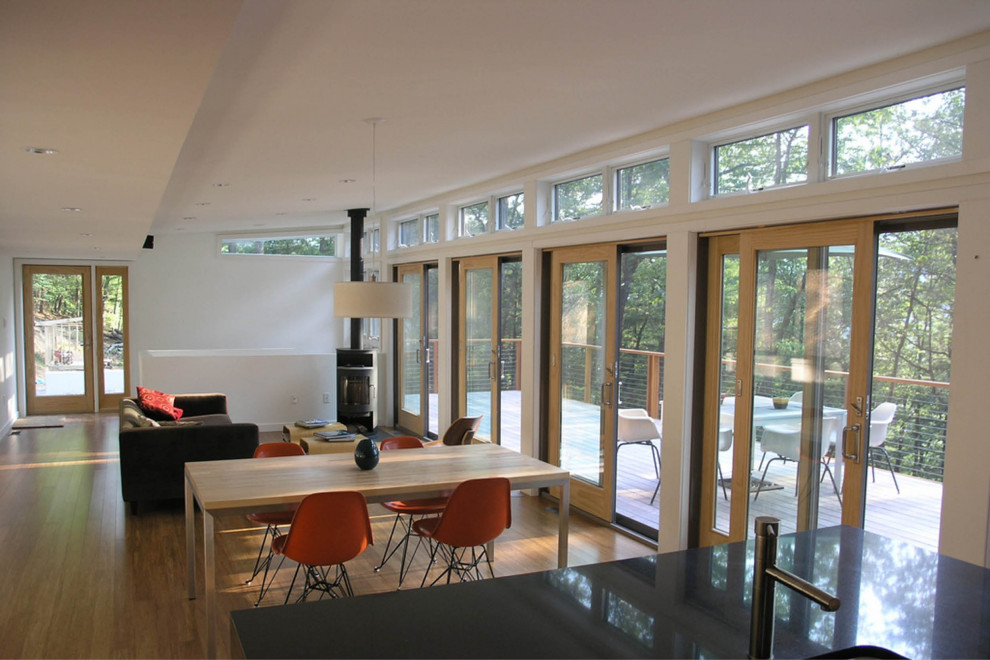 Esempio di un soggiorno minimalista di medie dimensioni e aperto con pareti bianche, pavimento in legno massello medio e stufa a legna
