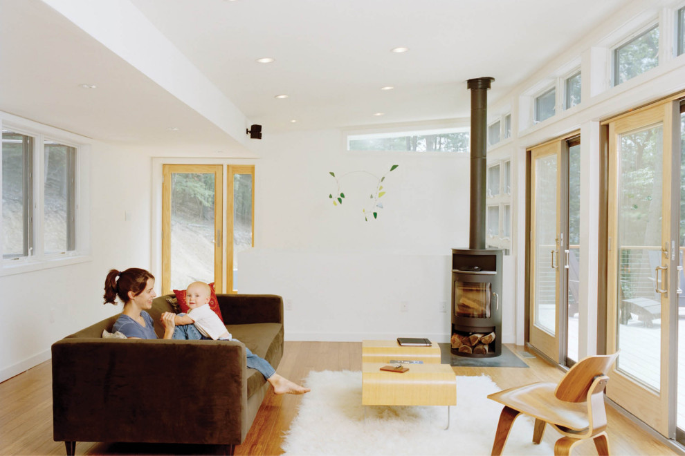 Immagine di un soggiorno moderno di medie dimensioni e aperto con pareti bianche, pavimento in legno massello medio e stufa a legna