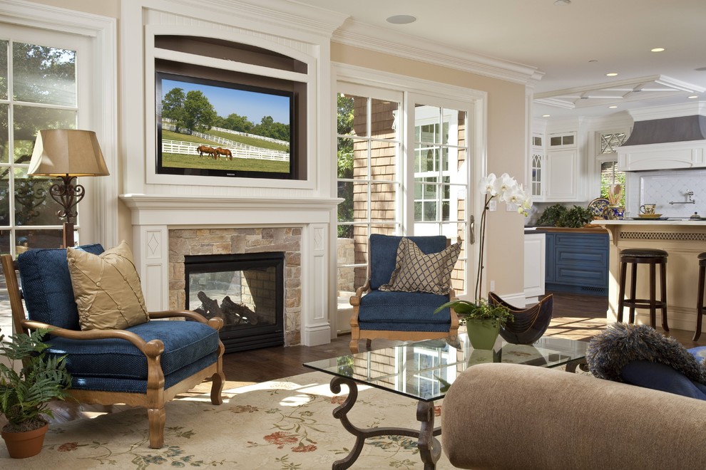 Immagine di un soggiorno classico con pareti beige, camino classico, TV a parete e tappeto