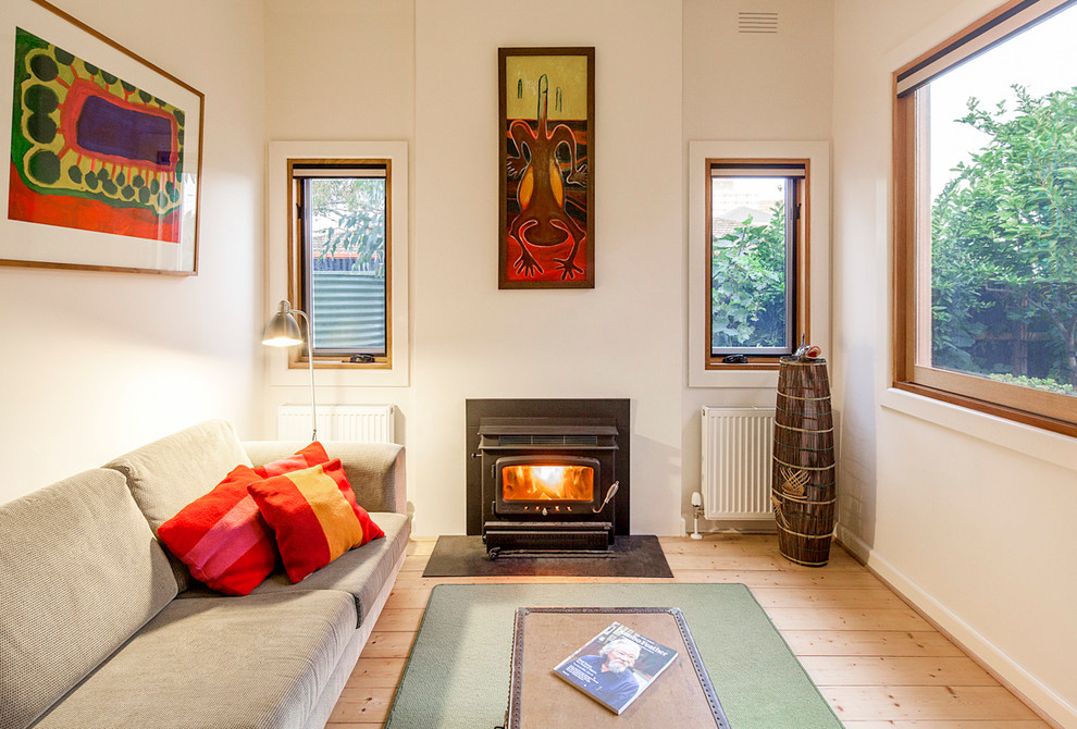 Mittelgroßes, Fernseherloses, Abgetrenntes Klassisches Wohnzimmer mit weißer Wandfarbe, hellem Holzboden, Kaminofen und Kaminumrandung aus Metall in Melbourne