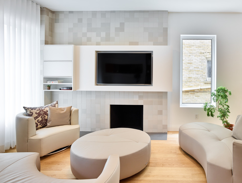 Cette photo montre un salon tendance avec un mur blanc, parquet clair, une cheminée standard, un manteau de cheminée en carrelage et un téléviseur encastré.