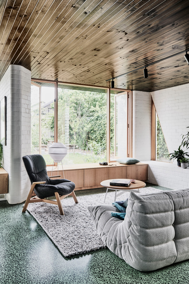 Mittelgroßes, Offenes Modernes Wohnzimmer mit weißer Wandfarbe, Betonboden, Kaminofen, Kaminumrandung aus Metall und grünem Boden
