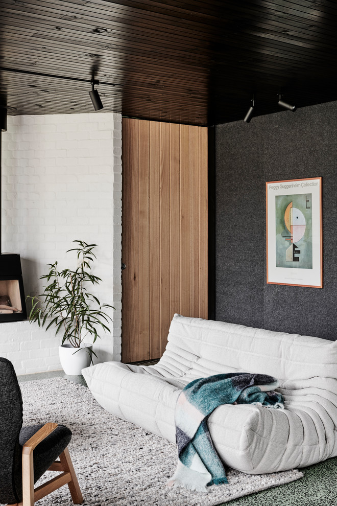 Modern inredning av ett mellanstort allrum med öppen planlösning, med vita väggar, betonggolv, en öppen vedspis, en spiselkrans i metall och grönt golv
