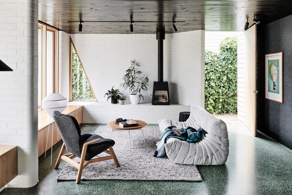 На фото: открытая гостиная комната среднего размера в современном стиле с бетонным полом, печью-буржуйкой, фасадом камина из металла, зеленым полом и белыми стенами