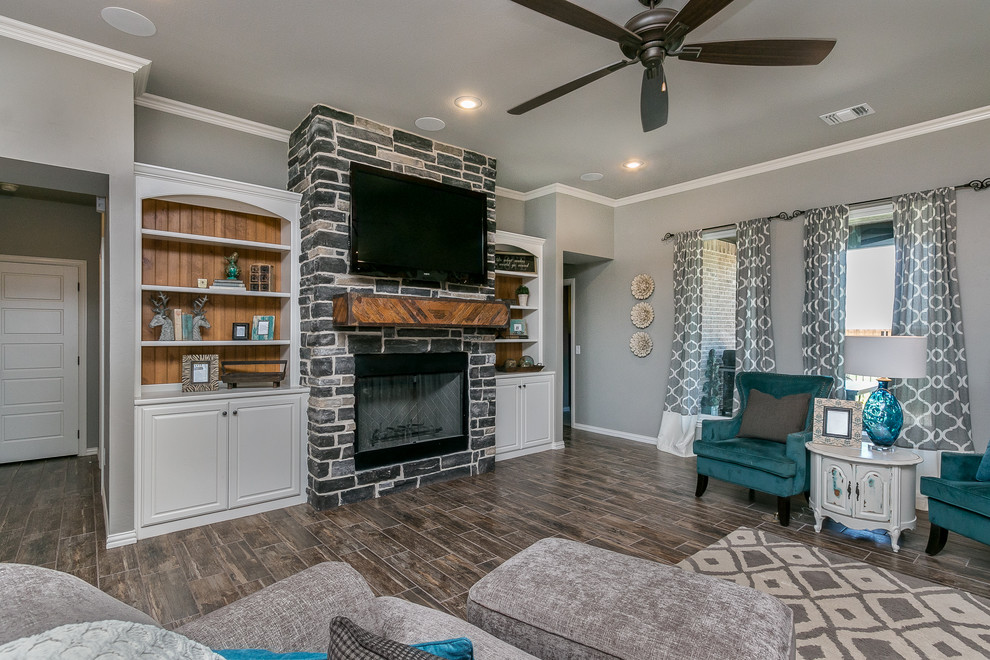 Modernes Wohnzimmer mit beiger Wandfarbe, Sperrholzboden, Kamin, Kaminumrandung aus Stein, TV-Wand und braunem Boden in Dallas