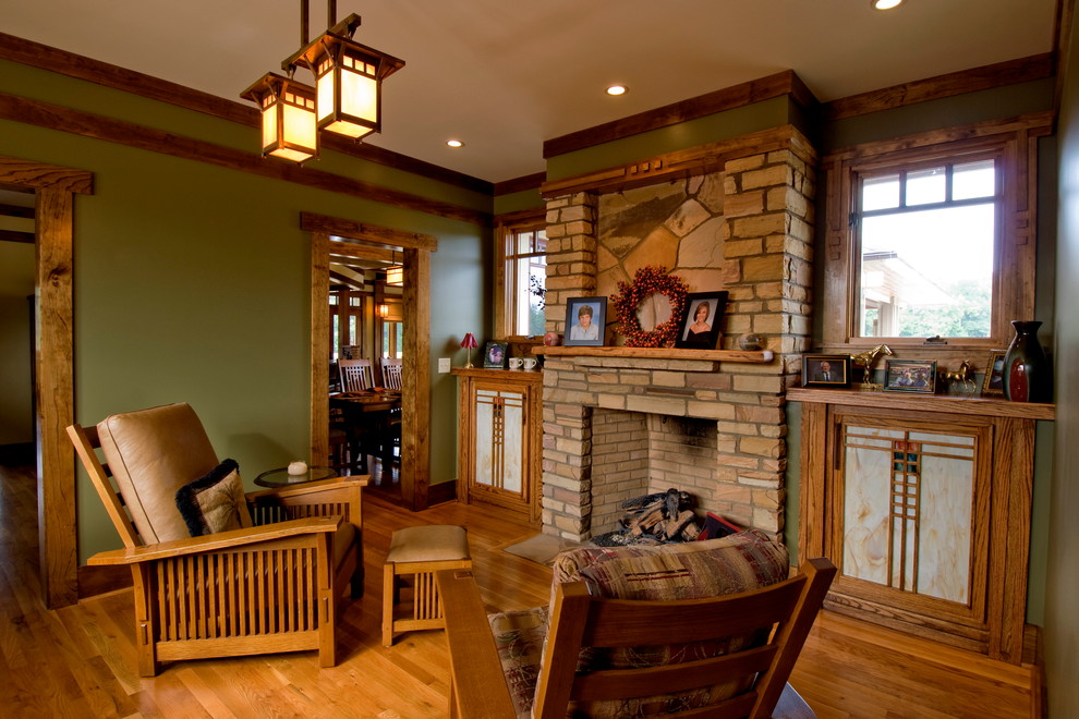 Abgetrenntes Rustikales Wohnzimmer mit grüner Wandfarbe, braunem Holzboden, Kamin und Kaminumrandung aus Stein in Sonstige