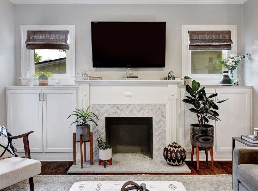 На фото: изолированная гостиная комната среднего размера в стиле неоклассика (современная классика) с серыми стенами, темным паркетным полом, стандартным камином, фасадом камина из плитки, телевизором на стене и коричневым полом