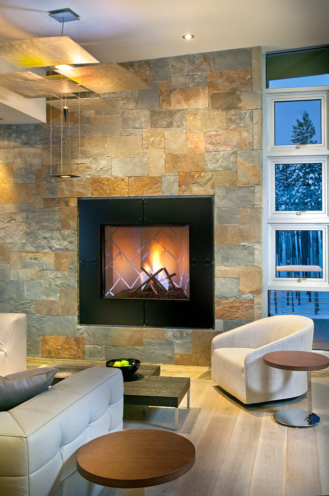 アトランタにあるラグジュアリーな巨大なコンテンポラリースタイルのおしゃれなリビング (石材の暖炉まわり、淡色無垢フローリング、標準型暖炉、テレビなし、グレーの壁、グレーの床) の写真